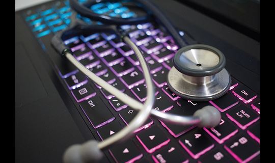Stethoscope laying on top of a glowing keyboard