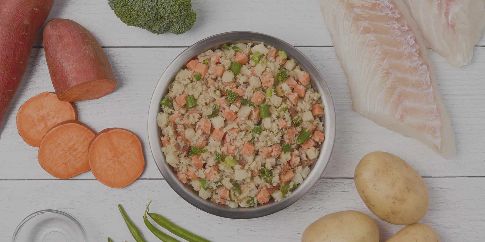 Bowl of JustFoodForDogs with fresh ingredients around it