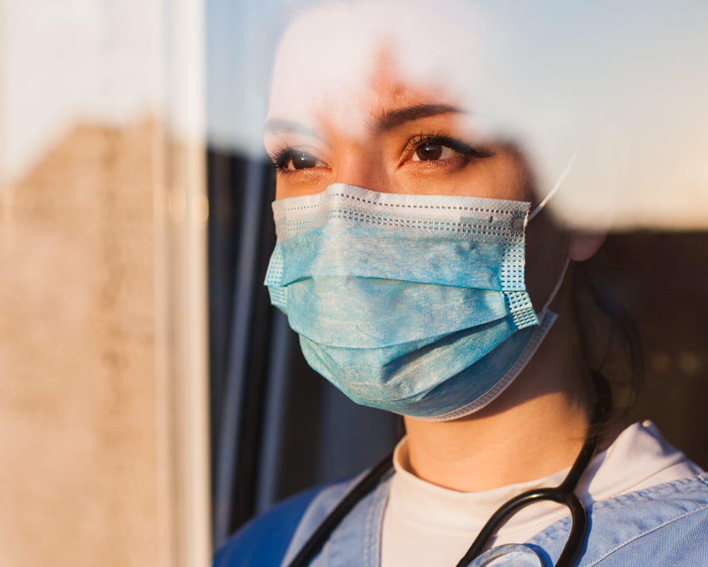 Veterinarian with mask looking out a window