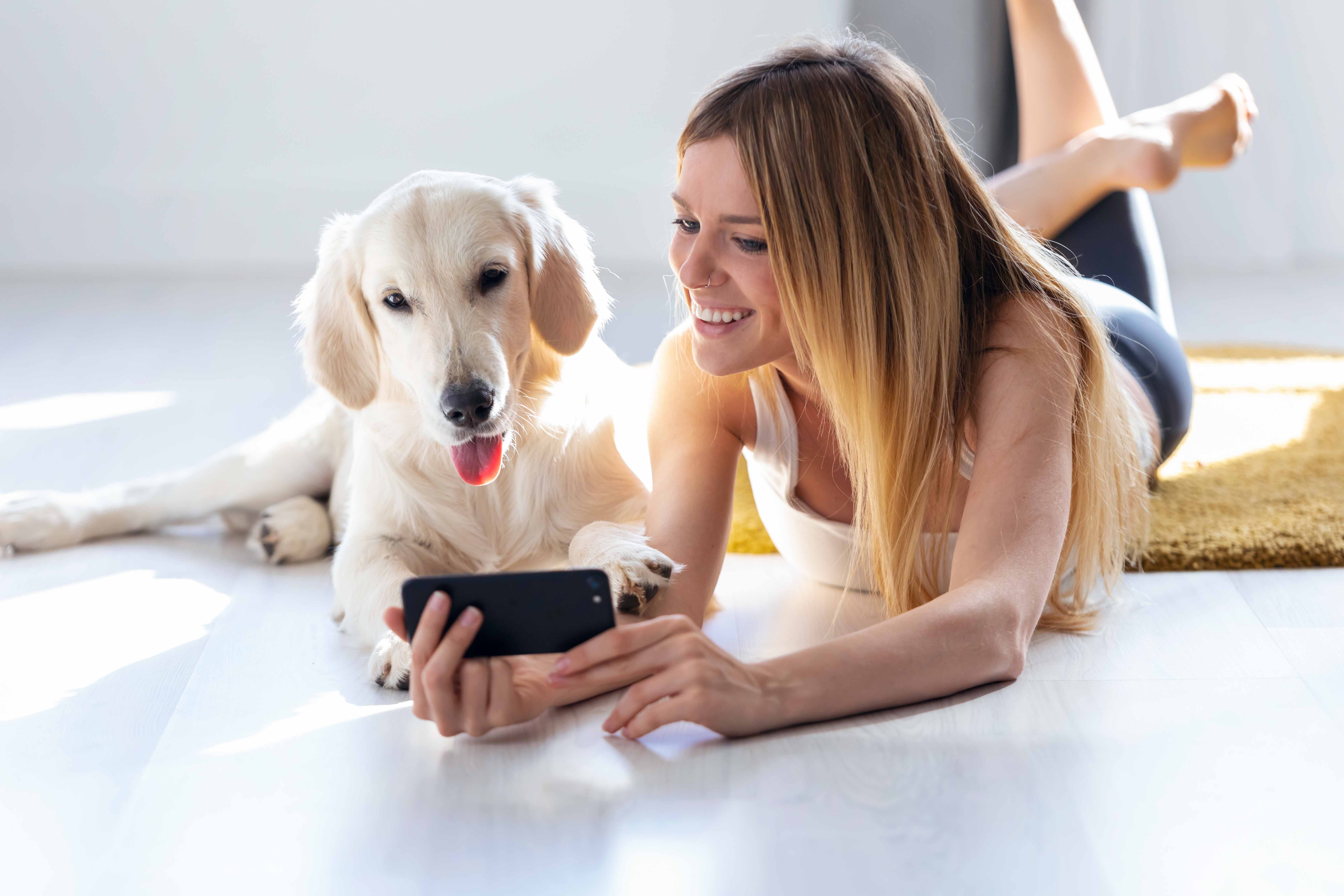 women and dog on floor looking at phone screen